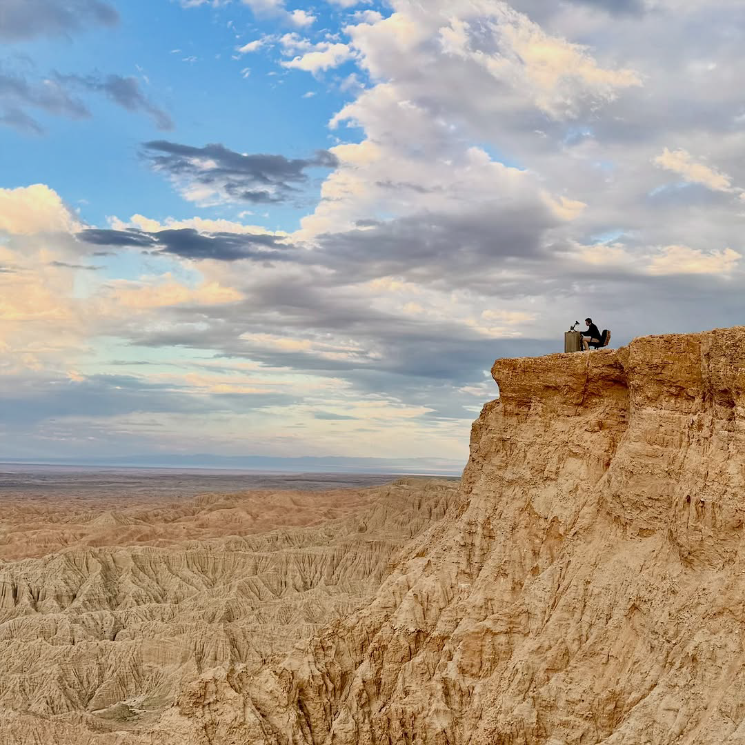 Scotty working from his desk on the edge of a desert cliff